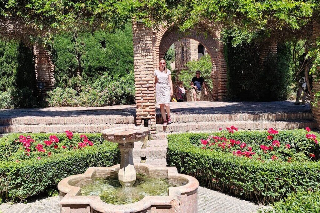 A Spanyolban Otthon blog szerzője az Alcazaba mór erőd kertjében, rózsák és szökőkutak között. Malaga látnivalók tippek 2026.