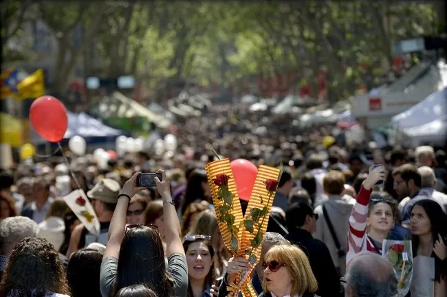 tömeg Barcelonában a La Ramblán, egy nő két rózsát fog, és egy piros lufi felszáll